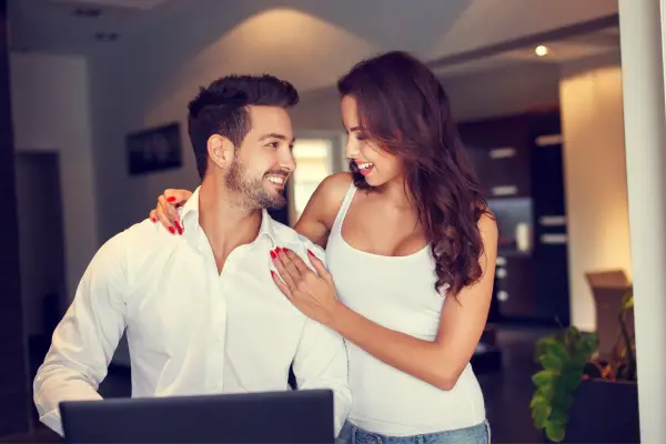 happy smiling couple at with in front laptop