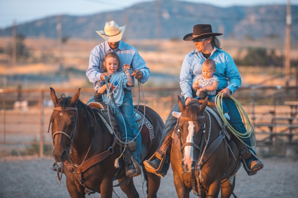 parents riding horses with kids 