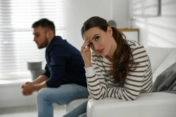 young couple after fight sitting in home at sofa