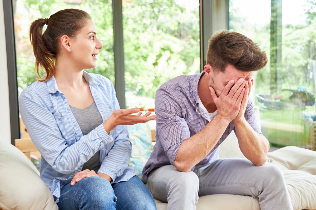 wife talking, sad husband covering face with hands