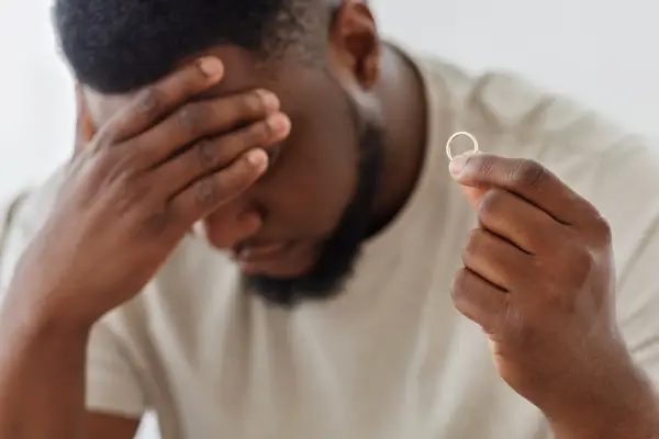 black man holding marriage rang thinking about end of marriage divorce