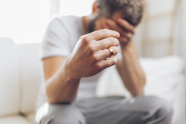 man holding marriage ring in hands depression