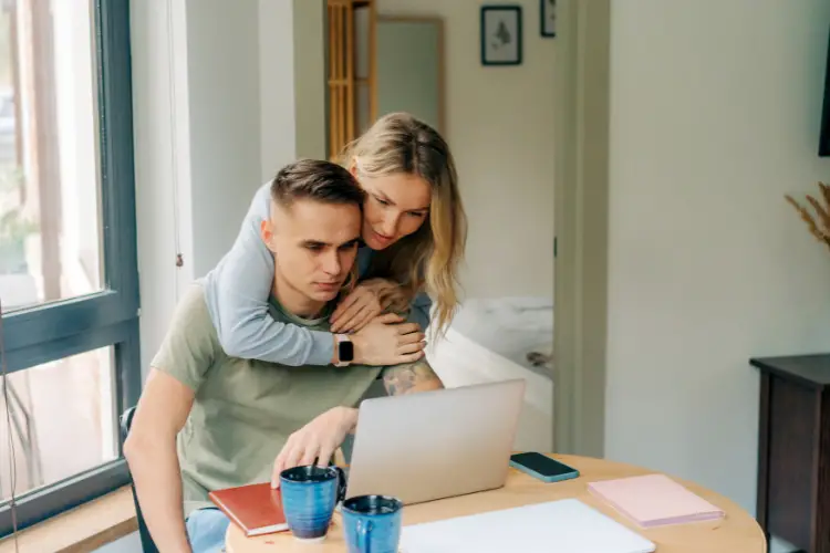 girl hugging guy while he works from home