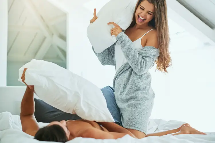 husband wife pillow fight in bed